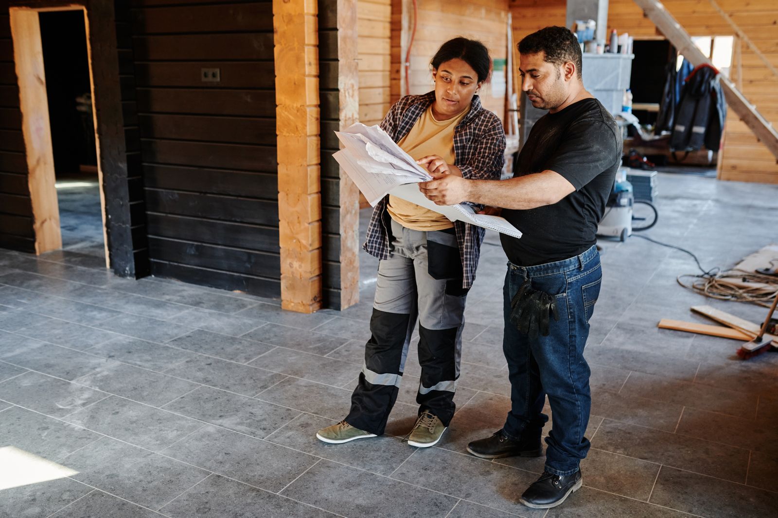 Two people going over papers inside a house under construction