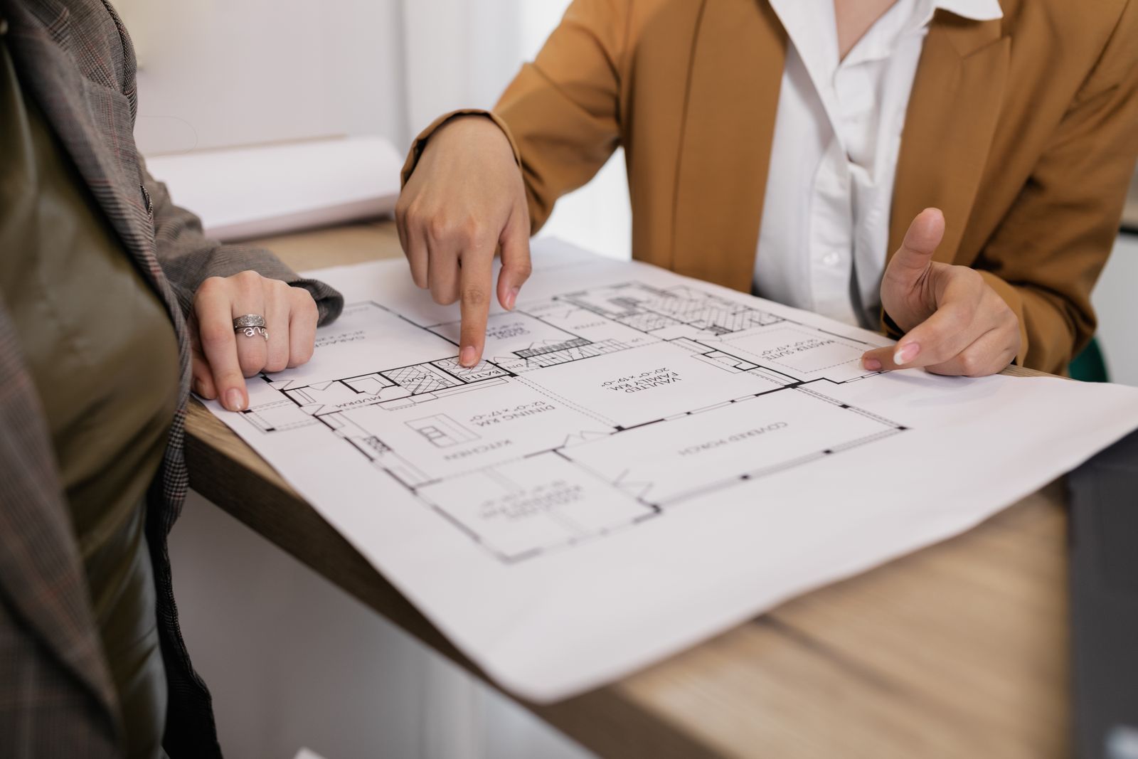 Two people pointing at a house floor plan on a table