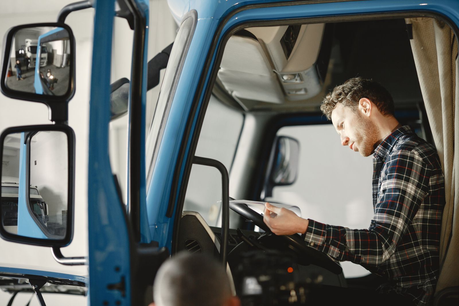 A man reading paperwork in the cab of a blue work truck